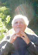 portrait of Douglas Engelbart, hands clasped in a prayer pose, sunlight glinting behind him like a halo.